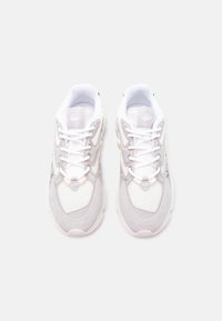 Λευκά και ανοιχτόγκρι αθλητικά παπούτσια με λεπτομέρειες από δίχτυ και σουέντ, λευκά κορδόνια και διακριτικό λογότυπο στη γλώσσα, εμφανιζόμενα από πάνω.