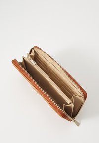 Portefeuille en tissu marron avec fermeture zippée, comportant plusieurs emplacements pour cartes, un compartiment central zippé et un intérieur beige lisse.