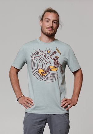 Hellblaues Baumwoll-T-Shirt mit einem Grafikan design eines Skeletts, das auf einer Welle surft, mit gelben Shorts und braunen Linienelementen.