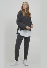 Gray ribbed knit sweater with long sleeves, layered over a white shirt. Matching gray ribbed pants and white sneakers complete the look.