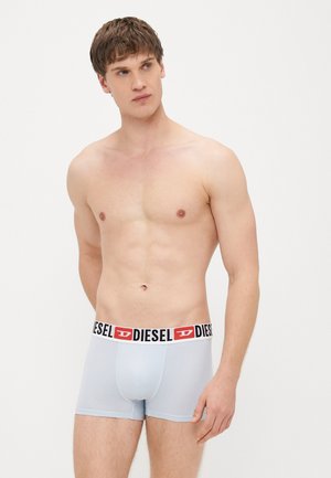 Világoskék boxeralsó fekete derékpánttal, amelyen piros "D" logó látható. Az anyag sima és rugalmas, kényelmet biztosítva.