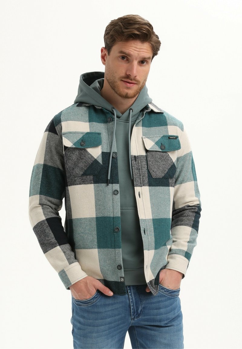 Geruite flanellen overhemd in teal, wit en grijs met twee borstzakken, knoopsluiting en een gestructureerde afwerking, gedragen over een grijze hoodie.