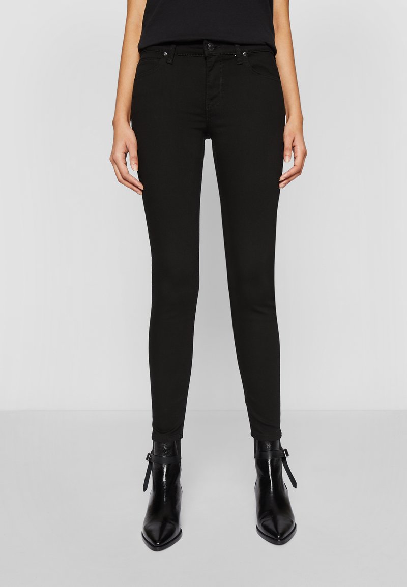 Jeans negros ajustados con un corte Slim Fit, que presentan un diseño clásico de cinco bolsillos, herrajes metálicos y una tela de algodón elástico y suave.