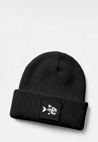 Black beanie hat with vertical ribbed texture, featuring a rectangular patch with a white fishbone graphic. Soft, stretchy material.