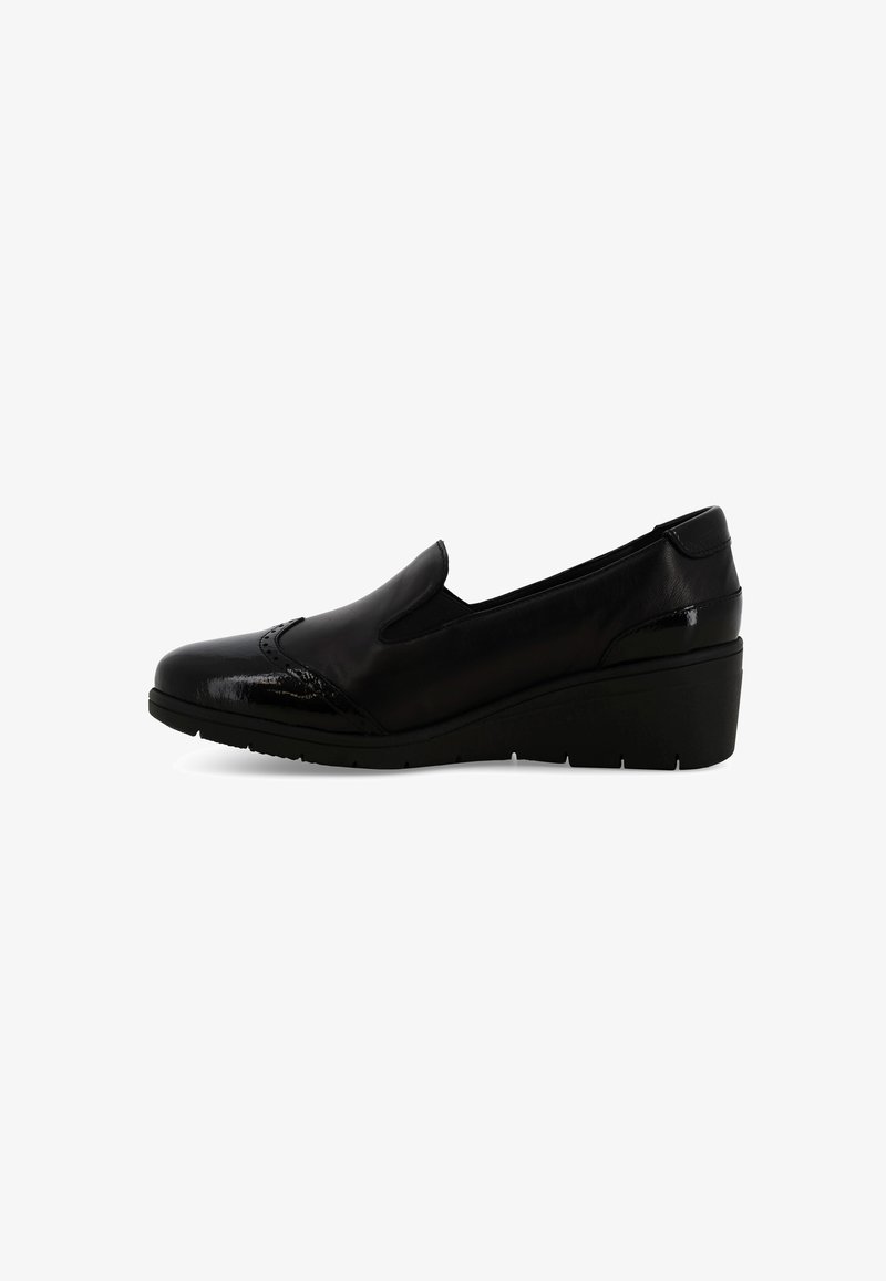 Scarpa slip-on in pelle nera con dettagli brogue e una spessa suola a cuneo, vista di lato su uno sfondo bianco.