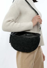 Borsa a mezzaluna nera realizzata in materiale testurizzato con chiusura a zip, dotata di una tracolla nera liscia e di un logo impresso sul davanti.