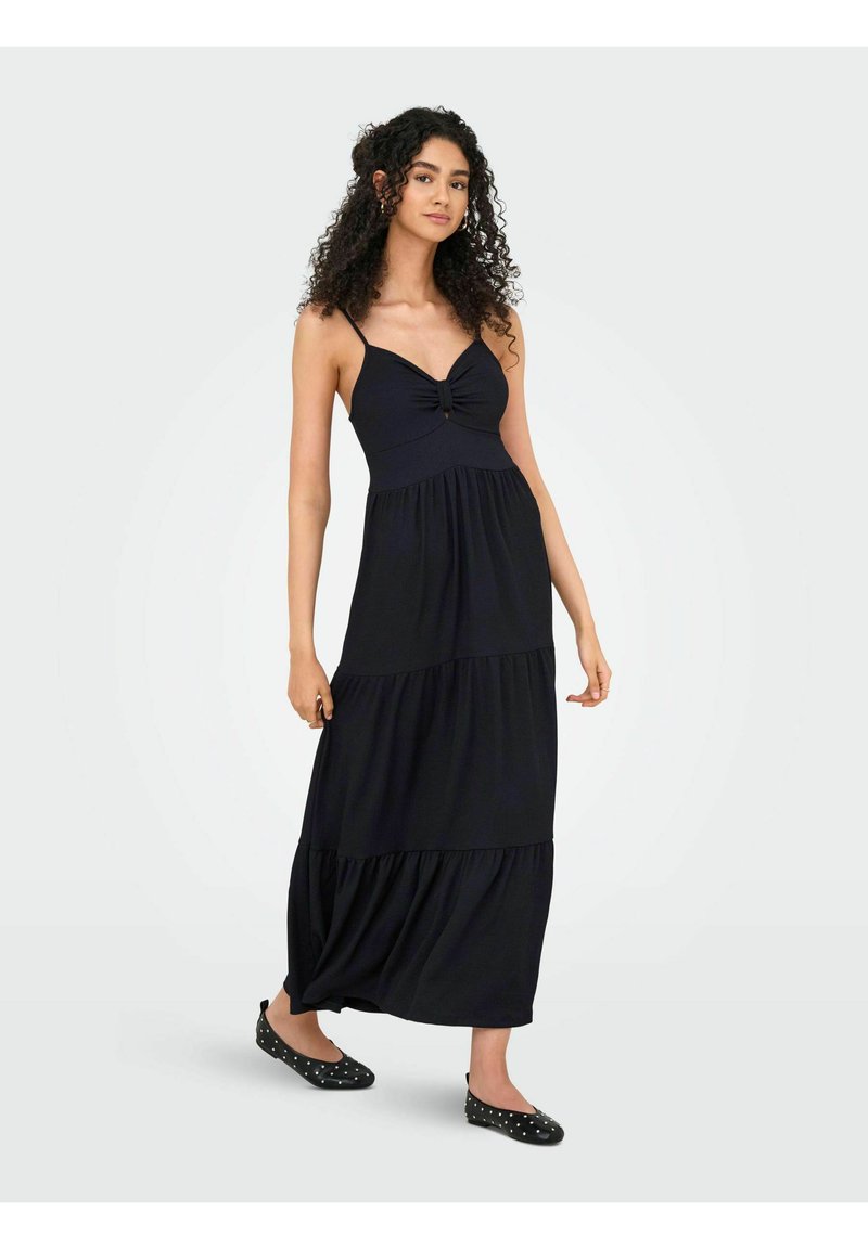 Robe maxi noire avec un corsage ajusté, un détail central noué et une jupe à volants. Fabriquée en tissu doux, elle présente de fines bretelles spaghetti.