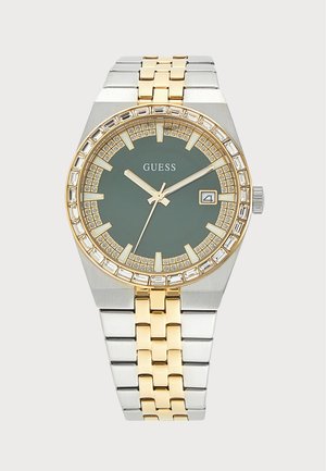 Montre-bracelet Guess pour homme avec bracelet en métal doré et argenté, cadran vert foncé, lunette ornée de cristaux et affichage de la date à 3 heures.