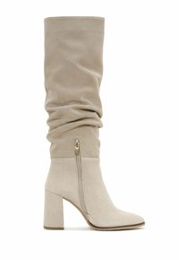 Stivali beige in suede con gambale morbido e zip laterale. Design con tacco a blocco e punta affusolata. Texture liscia.