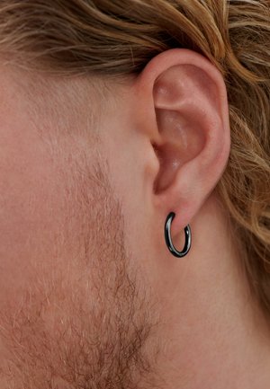 Svart metall ringøredobb på en nærbilde av et øre. Øredobben har en glatt, skinnende overflate og et sirkulært design.