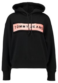 Sudadera negra con un parche rectangular rosa y texto negro "TOMMY JEANS" en el pecho, con capucha ajustable y puños acanalados.