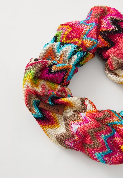 Elastic de păr tricotat, multicolor, cu modele în zigzag în nuanțe de roz, portocaliu, albastru și marron, având un mic etichetă din piele marron inscripționată cu 'MISSONI'.