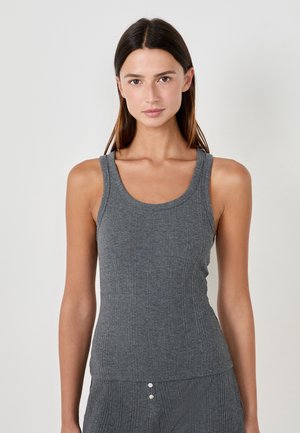Canotta grigia a coste con spalline larghe e scollatura arrotondata, caratterizzata da un design aderente e una leggera texture, abbinata a pantaloni coordinati.