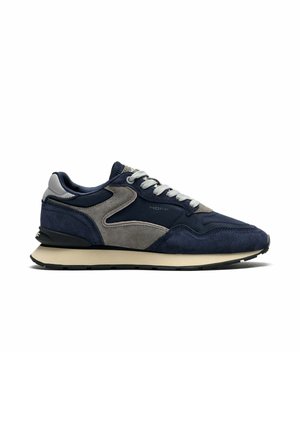Zapatilla de ante azul marino y gris con cordones blancos, media suela beige, suela negra y logo "HOFF" en el lateral.