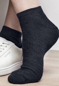 Ciemnoszara skarpetka do kostki wykonana z teksturowanej tkaniny, z prążkowanym wzorem i lekkim uczuciem, zestawiona z białym trenerem.