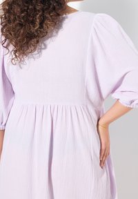 Lilafarbene Baumwollkleid mit Puffärmeln, strukturiertem Stoff, gestuftem Design und gerafftem Taillenbereich, das eine lockere Silhouette präsentiert.