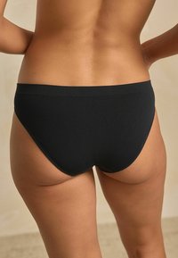 Culotte de bikini en coton noir avec une texture lisse et une coupe taille basse, présentant une taille simple sans matériel ou accents visibles.