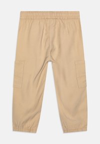 Pantalones cargo color caqui con una cinturilla elástica, que cuentan con dos bolsillos laterales, tejido ligero y puños elásticos en los tobillos.