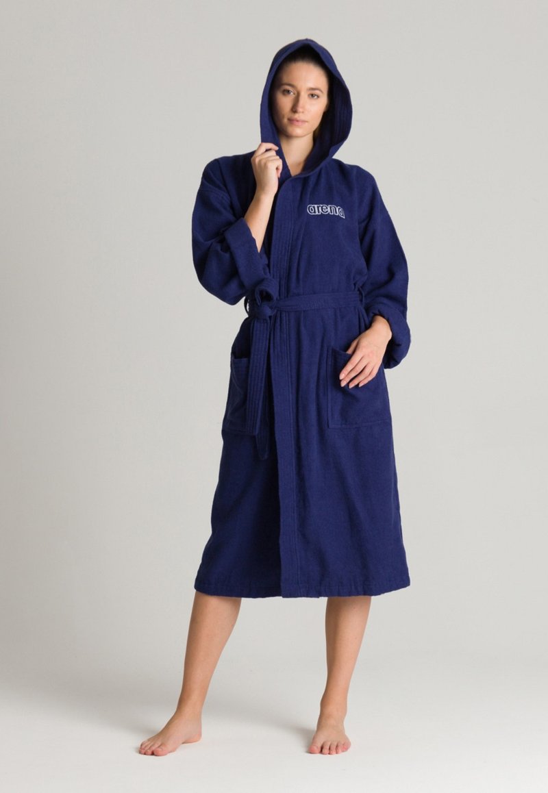 Accappatoio con cappuccio di colore blu navy, realizzato in morbido cotone spugnoso, dotato di cintura in vita, due tasche frontali e dettagli a coste lungo il cappuccio e le maniche.