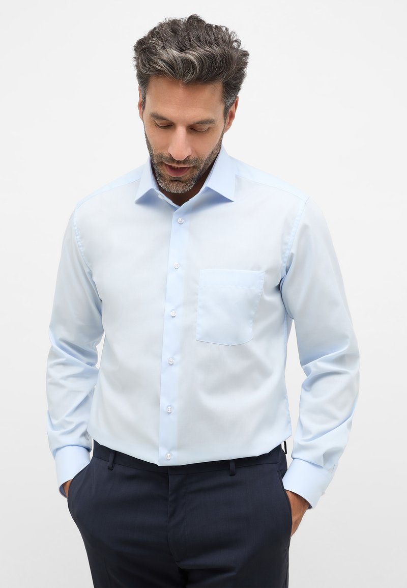 Lichtblauwe button-up shirt met een zak, lange mouwen en een netjes gestructureerde kraag, gecombineerd met donkere broeken. Gladde stoftextuur.