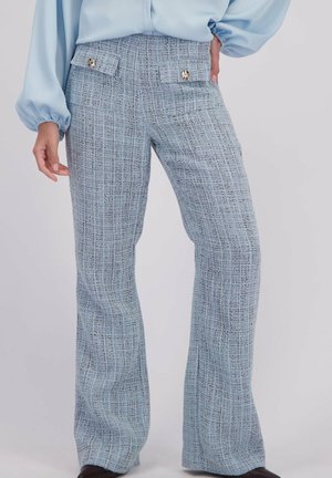 Lichtblauwe hoge taille wijde pijpen broek met een gestructureerd ruitenpatroon en decoratieve gouden knopen op de voorzakken, gedragen met een lichtblauwe blouse.