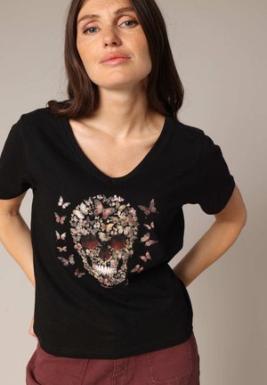 T-shirt noir à col en V avec un design de crâne floral et des papillons dans des nuances de rose et de blanc, fabriqué en coton doux.