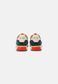 Sneakers verdi e crema con dettagli arancioni, dotati di una tomaia in suede, suola testurizzata e "1949" stampato sul tallone.