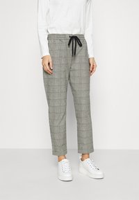 Grå rutiga byxor med elastisk midja, justerbar snörning och smal benform, kombinerat med vita sneakers. Slät tygtextur.