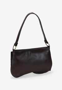 Bolso de mano de cuero marrón oscuro con un borde inferior curvado y una sola correa para el hombro unida por anillos de tono dorado.