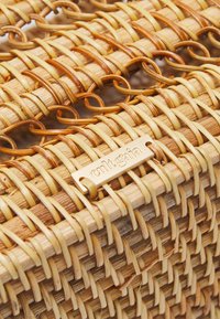 Vævet kurv af naturlig rattan med rektangulær form, lys brun farve og en guldfarvet metaltag med indgraveret "cult gaia".