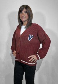 Cardigan marrone lavorato a maglia con strisce bianche e una toppa a V blu. Presenta chiusura con bottoni e maniche lunghe, tessuto strutturato.