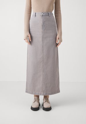 Lys grå denim maxiskjørt med en rett silhuett, to frontlommer og knappelukking i livet; kombinert med beige snøresko.