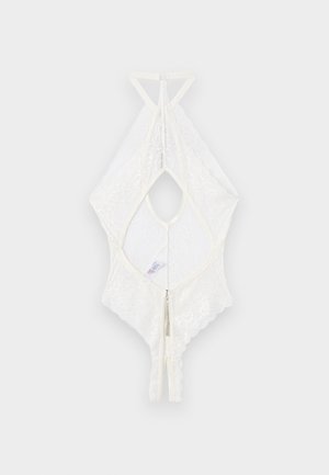 Body bianco in pizzo con collo halter, zip sul retro e design aperto a forma di chiave, disteso su uno sfondo grigio chiaro.