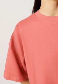 Koraalkleurig katoenen t-shirt met een klassieke ronde halslijn en korte mouwen. Soepele textuur en een casual pasvorm, met een eenvoudig ontwerp.
