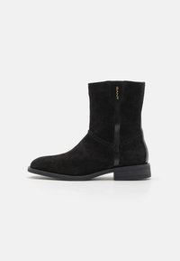 Bottines en suède noir avec un bout rond, des coutures subtiles et un accent noir brillant. Elles disposent d'un petit talon et du logo GANT sur le côté.