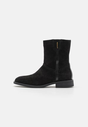 Bottines en suède noir avec un bout rond, des coutures subtiles et un accent noir brillant. Elles disposent d'un petit talon et du logo GANT sur le côté.