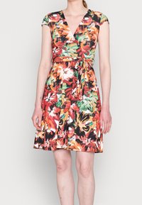 Kwiatowa sukienka w stylu wrap z dekoltem w kształcie litery V, krótkimi rękawkami i dopasowaną talią ze wstążką. Tkanina zdobiona jest żywymi wzorami w odcieniach czerwieni, pomarańczy i zieleni.