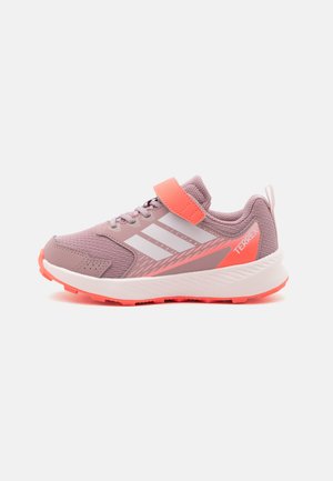 Παιδικό ροζ και κοραλλί αθλητικό παπούτσι Adidas Terrex με λευκές ρίγες, ιμάντα με βέλκρο και υφή στην σόλα, στραμμένο προς τα αριστερά σε λευκό φόντο.