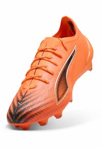 Orange fotbollssko med texturerad ovandel, svarta accenter och sex synliga dobbar. Den har en strömlinjeformad design och snörning framtill.