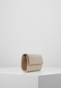 Béžová strukturovaná kabelka na rameno s texturovaným povrchem, vybavená překlopnou klopou a jemnými třpytivými akcenty. Kompaktní, obdélníkový tvar.