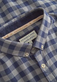 Camicia in cotone con motivo a quadretti blu navy e grigio, con colletto, un'etichetta interna e bottoni color crema.