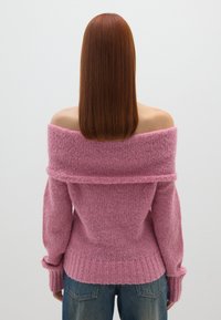 Rosa Schulterfreies Sweatshirt mit strukturiertem Strick, gerippten Bündchen und Saum. Trägt man zu blauen Jeans, von hinten präsentiert.