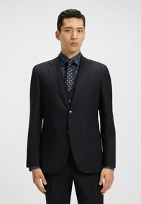Giacca nera con due bottoni, abbinata a una camicia a maniche lunghe blu con motivo e una cravatta a pois. Vestibilità su misura con tasche.