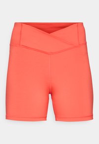 Coral workout shorts made of smooth fabric. Features a crossover waistband and stitched detailing, designed for comfort and flexibility.