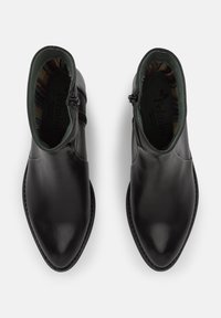 Botas de tobillo de cuero negro con punta afilada, cremallera lateral y un forro interior de patrón verde. Textura suave y diseño minimalista.