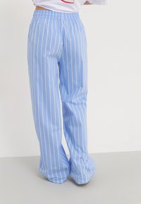 Pantalon large à rayures bleu clair, en tissu léger avec une ceinture élastique et une texture lisse, présentant des rayures blanches verticales.