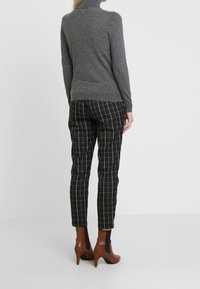 Gray turtleneck sweater, fitted design, paired with black and white checked trousers, and brown ankle boots with a black panel.