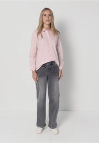 Light pink striped button-up shirt paired with gray wide-leg jeans and white sneakers. The shirt has a relaxed fit and soft texture.