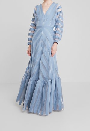 Vaaleansininen pitkähihainen maksimekko, jossa on V-pääntie. Mekko on valmistettu läpikuultavasta raidallisesta kankaasta ja siinä on röyhelöhelma. Vyötärö on istuvasti muotoiltu ja hihassa on puffit.