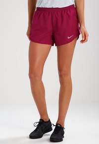 Krátké, lehké sportovní šortky v tmavé magentové barvě s elastickým pasem a bočními kapsami. Na levé straně je reflexní logo.